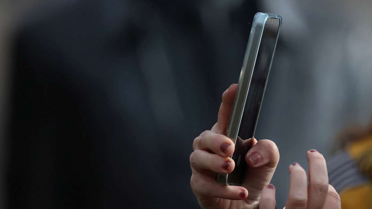 A woman uses a smartphone to take a photograph in Liverpool