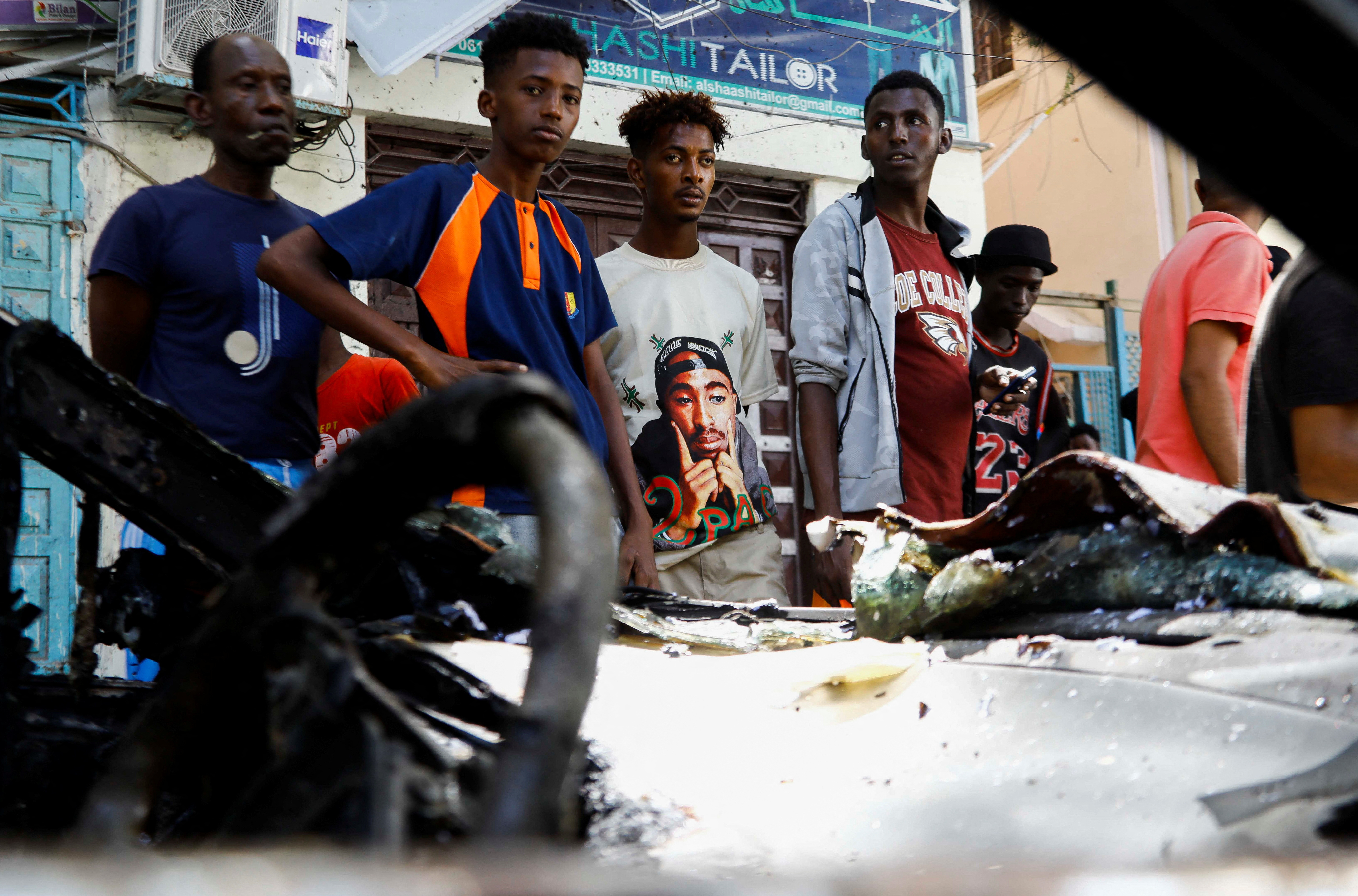 Somalis look at the wreckage of a vehicle destroyed at the scene of a suicide bomb blast in the Hamar Weyne district of Mogadishu