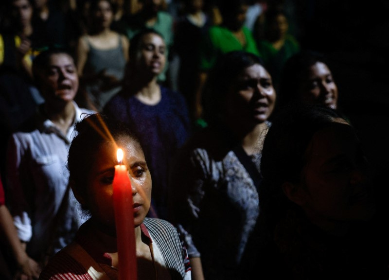 A woman holds a candle as she attends a candlelight vigil condemning the rape and murder of a trainee medic at a government-run hospital in Kolkata