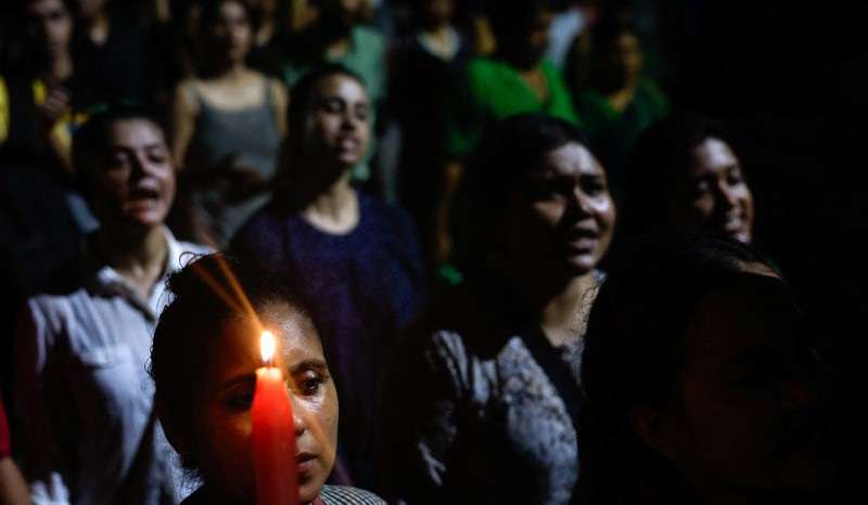 A woman holds a candle as she attends a candlelight vigil condemning the rape and murder of a trainee medic at a government-run hospital in Kolkata