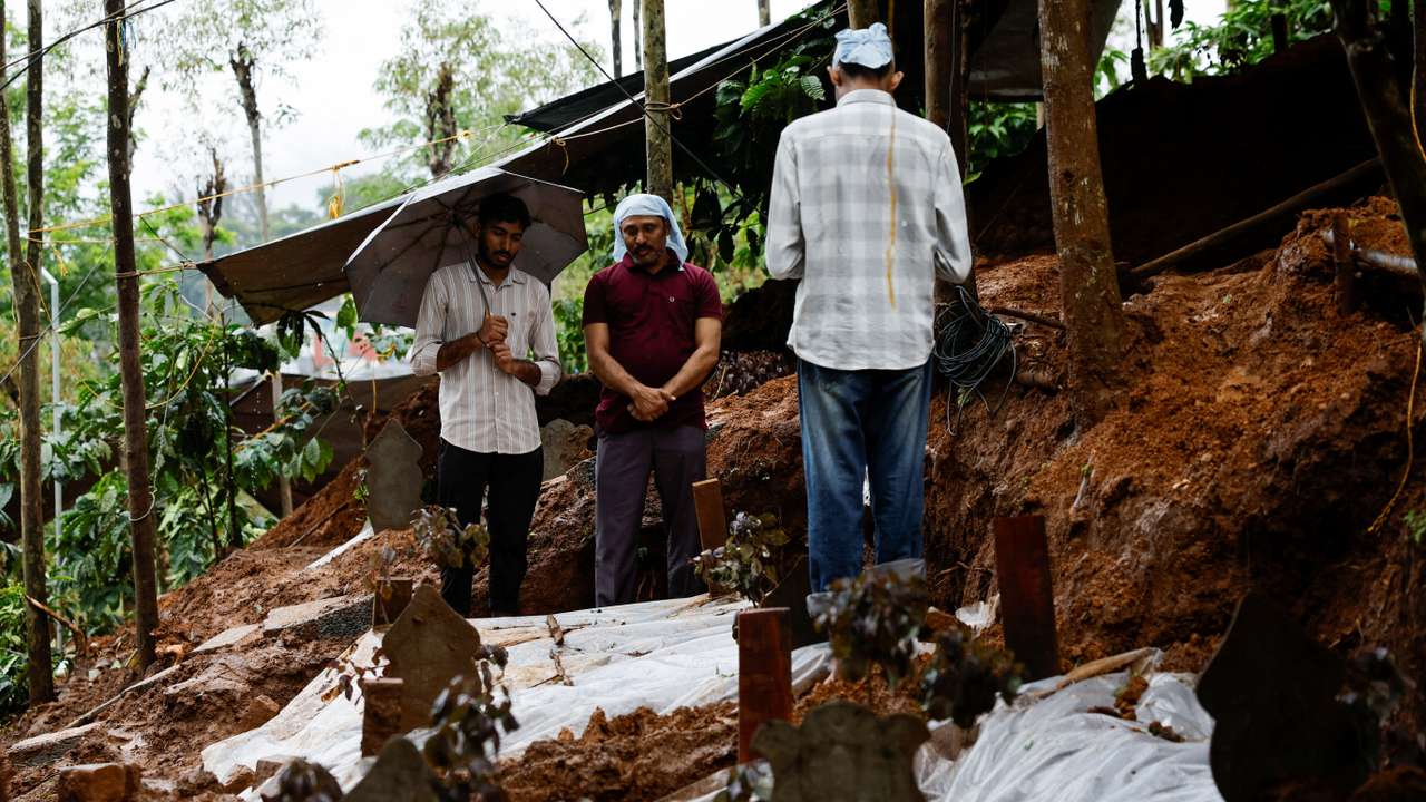 People pray for a departed family member at their grave after landslides hit several villages in Wayanad district, in Meppadi