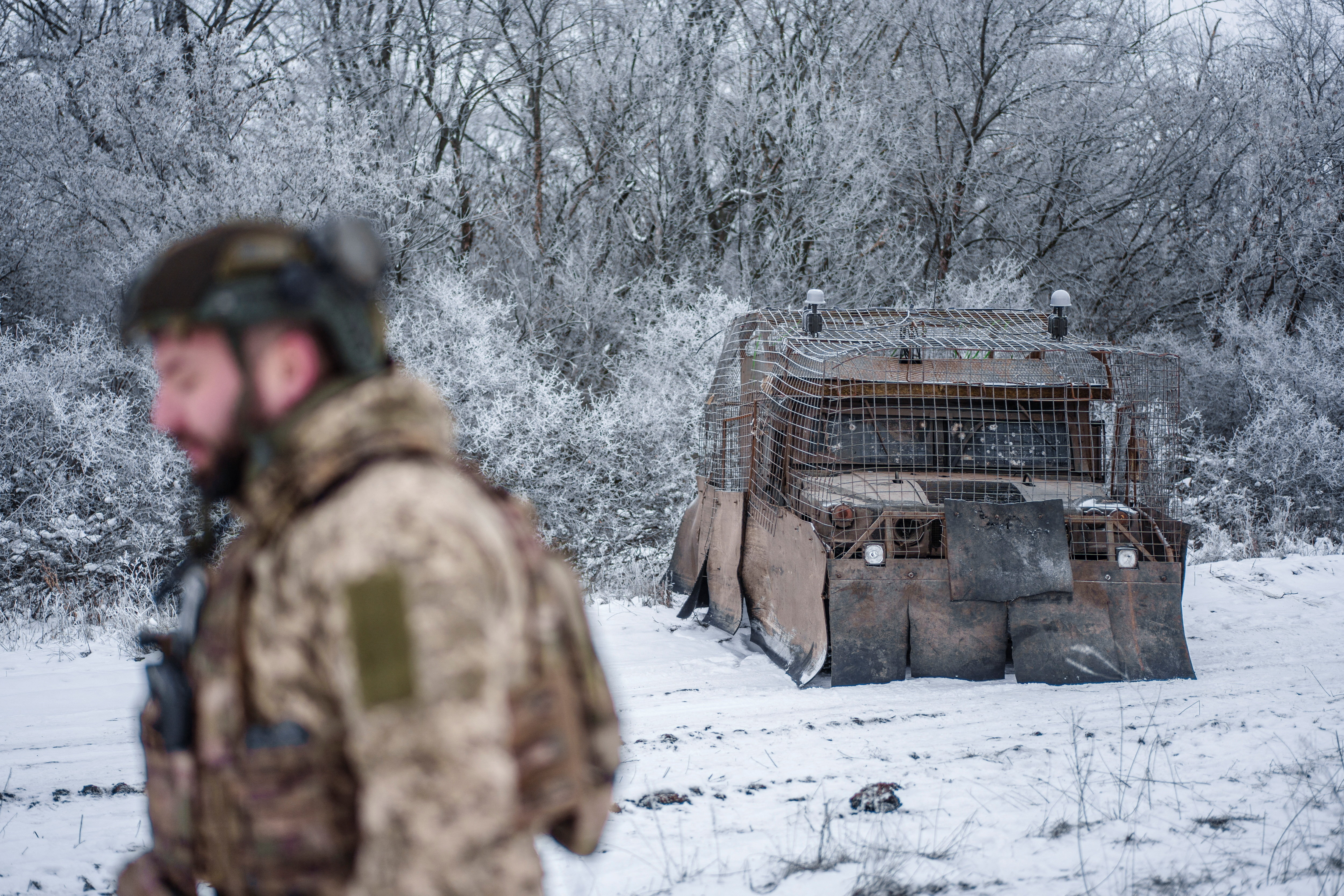 Ukrainian serviceman walks next to a Humvee covered with make shift anti-drone protection at a training ground near a front line in Donetsk region