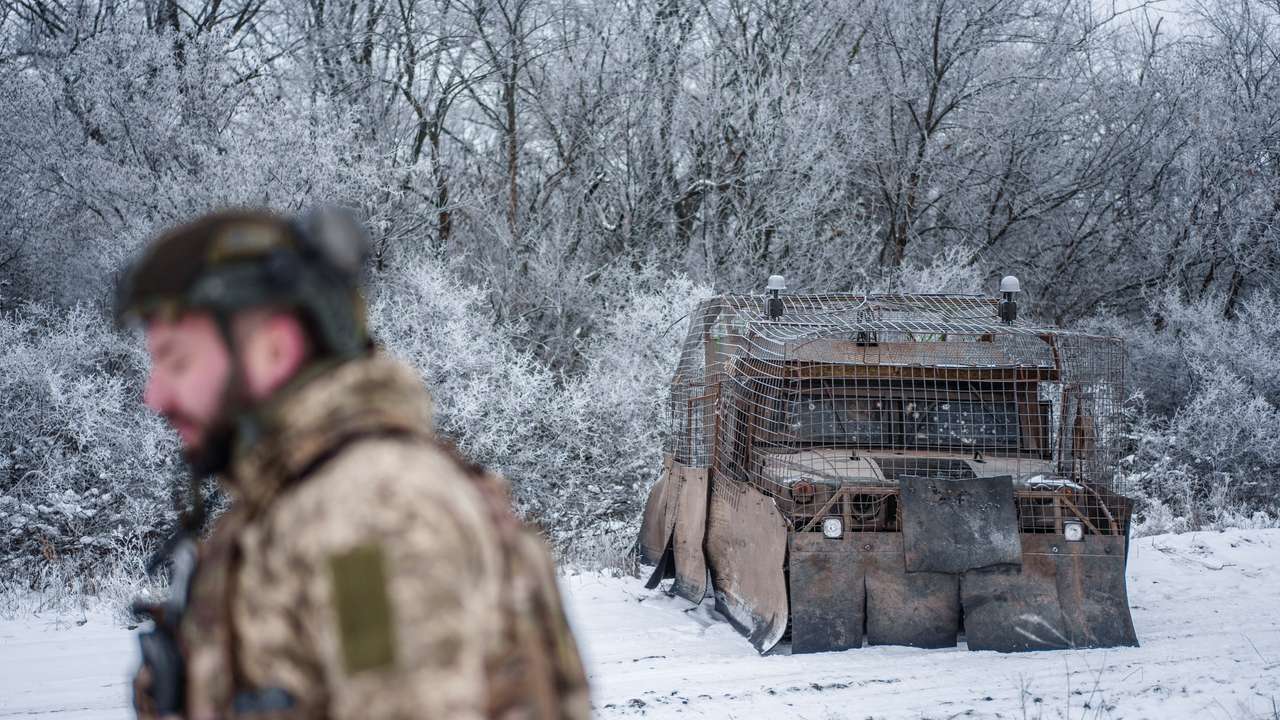 Ukrainian serviceman walks next to a Humvee covered with make shift anti-drone protection at a training ground near a front line in Donetsk region