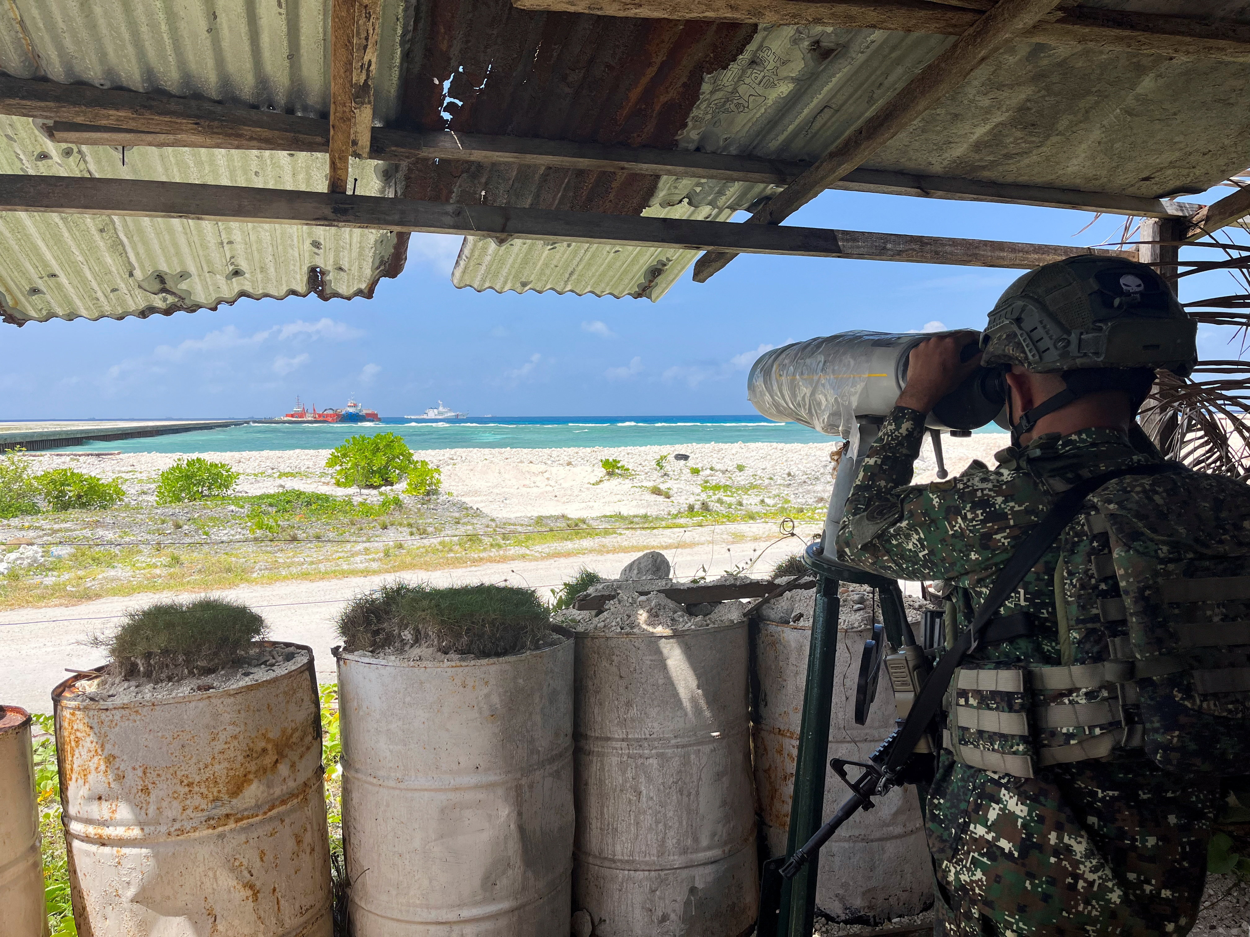 A Philippine soldier peers through an observation telescope from a viewing deck in Philippine-occupied Thitu Island in the disputed South China Sea