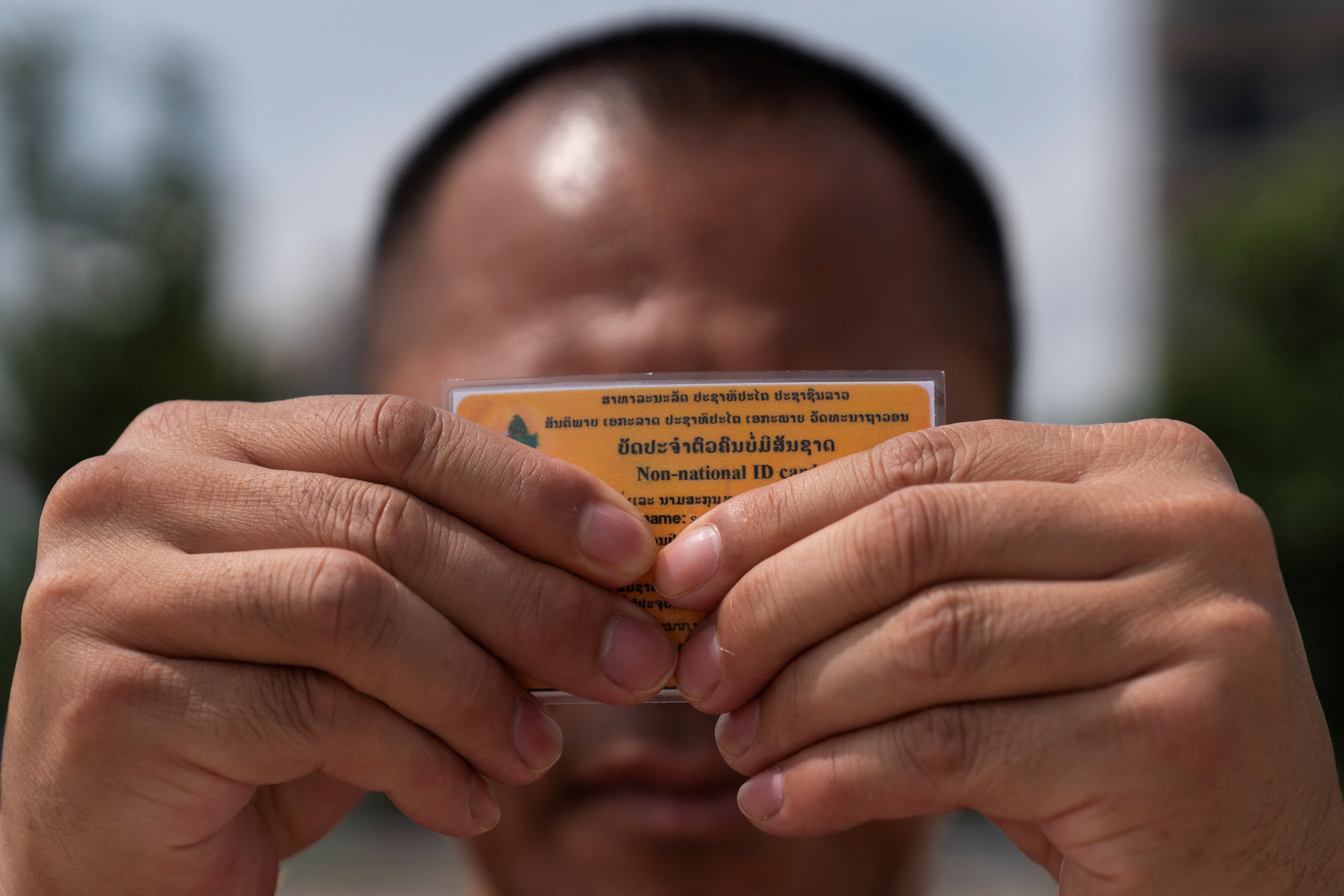 A Lao man deported from the U.S. holds up his non-national ID card, in Vientiane