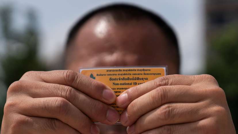 A Lao man deported from the U.S. holds up his non-national ID card, in Vientiane