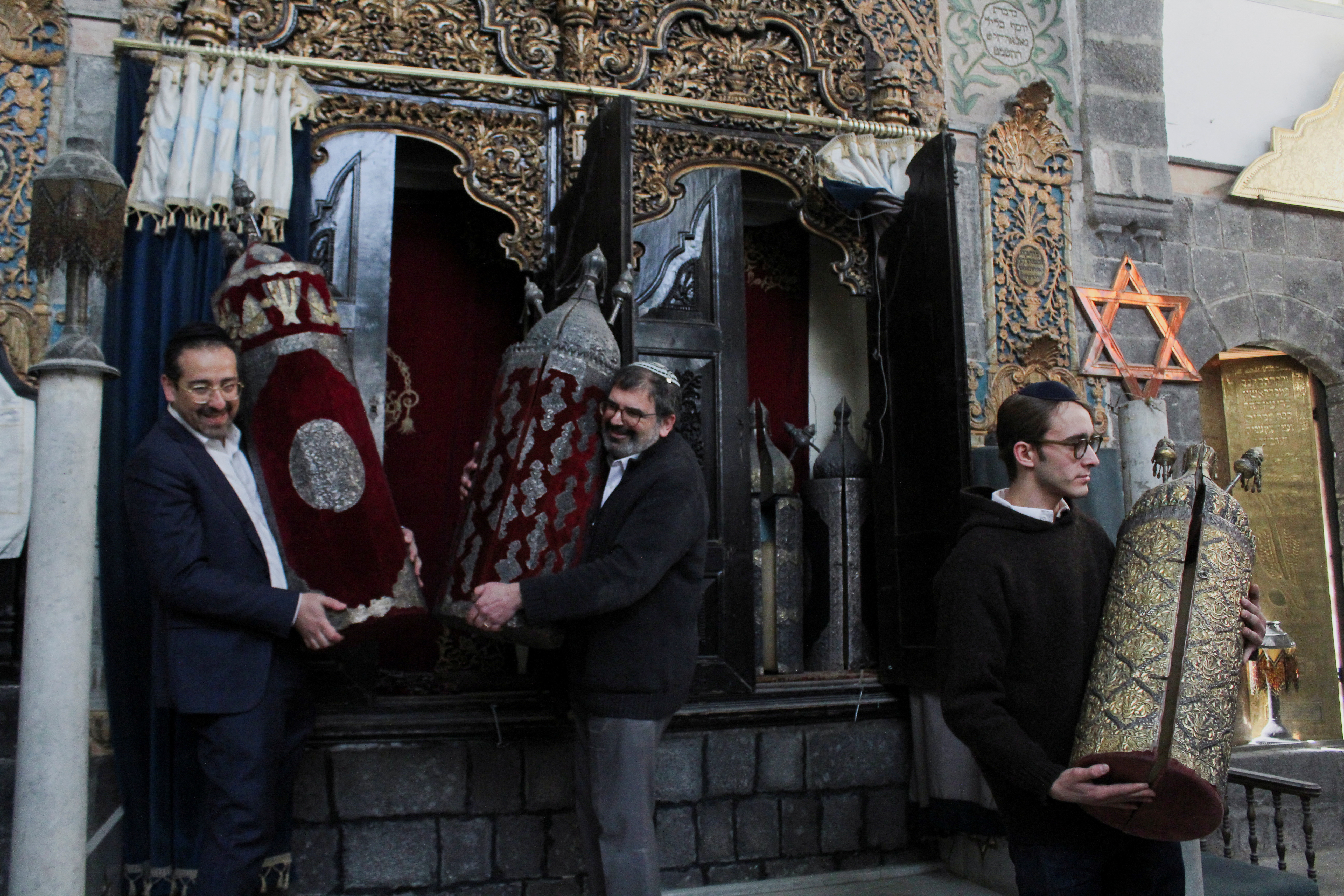 Henry Hamra and members of a Syrian Jewish delegation who are visiting Syria for the first time in decades hold a Torah Case in a Jewish synagogue in Damascus