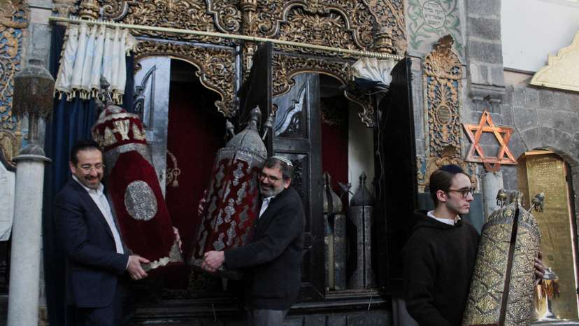 Henry Hamra and members of a Syrian Jewish delegation who are visiting Syria for the first time in decades hold a Torah Case in a Jewish synagogue in Damascus
