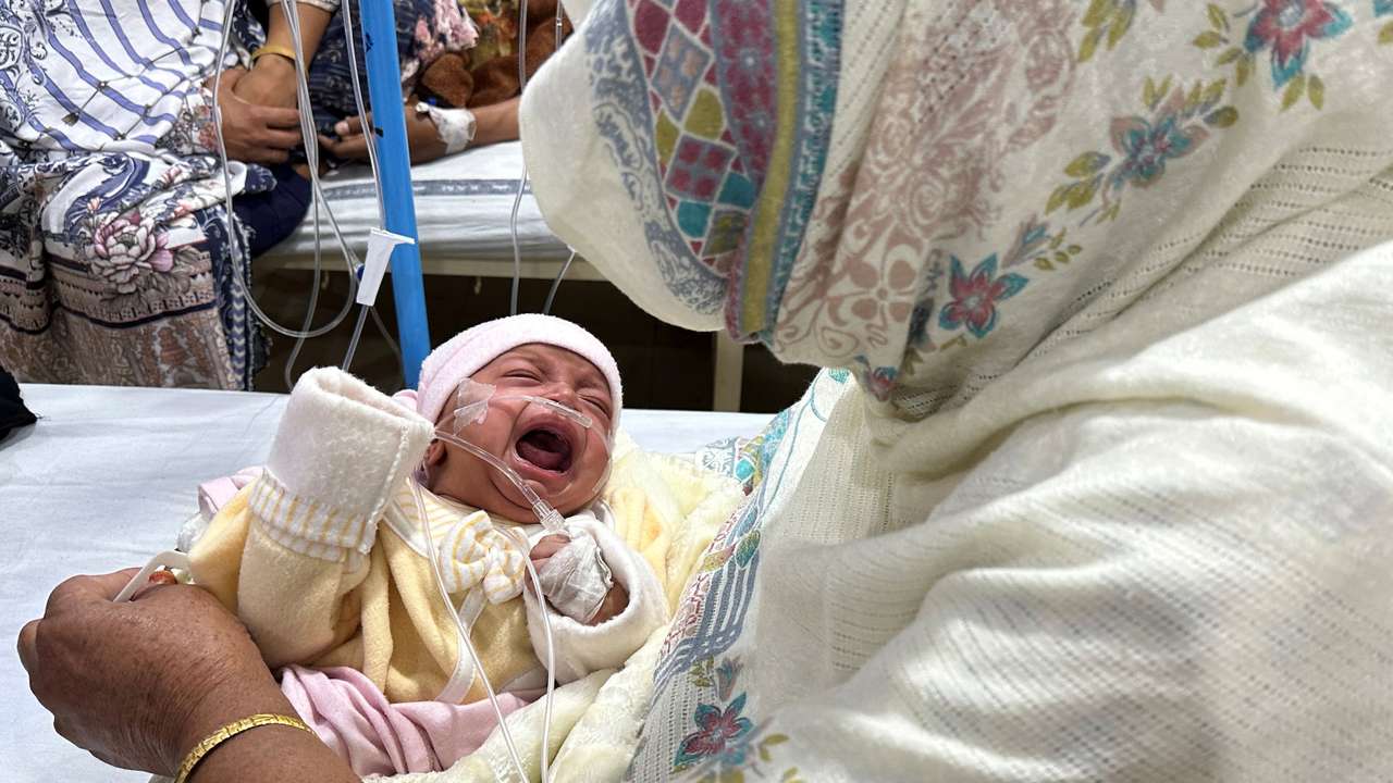 One-month old baby girl, Noor cries while being comforted by her grandmother inside the paediatric ward at Sir Ganga Ram hospital in Lahore