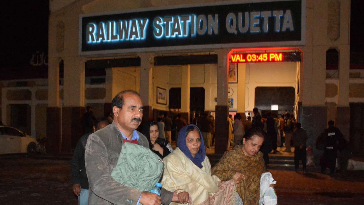 Passengers who were rescued from a train after it was attacked by separatist militants, walk with their belongings at the Railway Station in Quetta