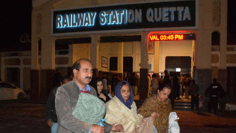 Passengers who were rescued from a train after it was attacked by separatist militants, walk with their belongings at the Railway Station in Quetta