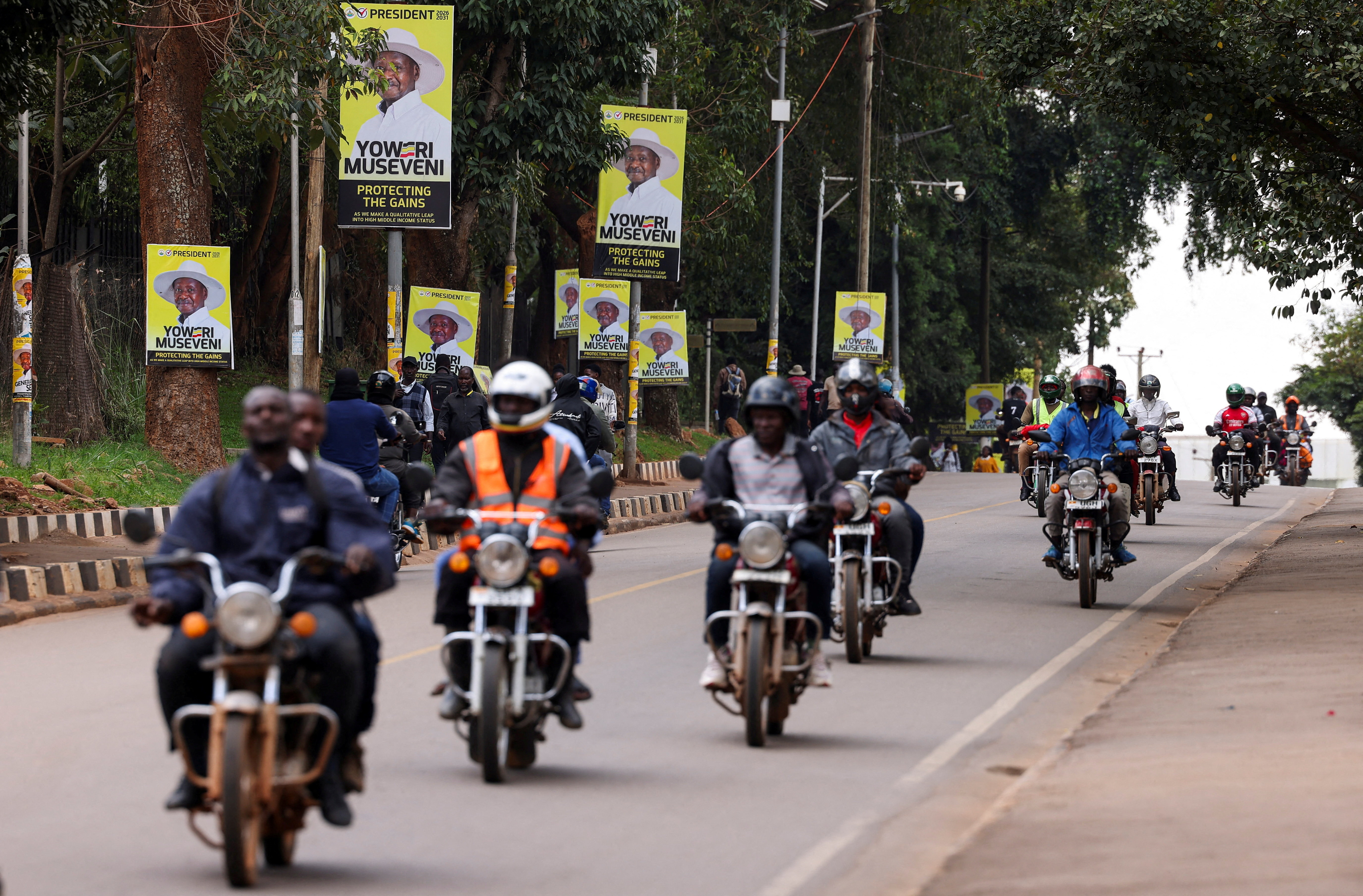 FILE PHOTO: Motorcycle taxis ride past campaign posters of Uganda's President Yoweri Museveni ahead of the upcoming general election in Kampala
