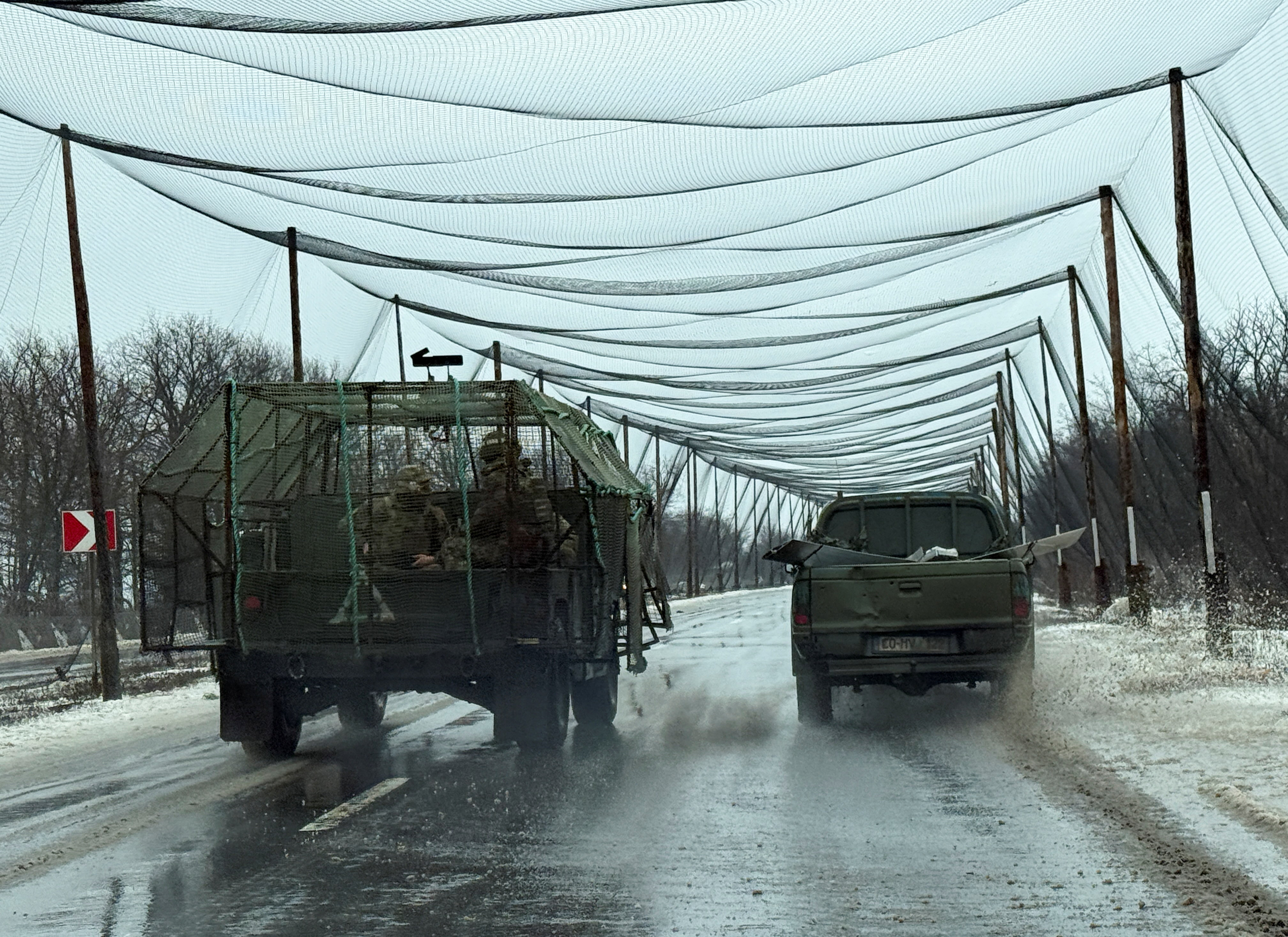 Ukrainian servicemen ride in a vehicle on a road covered with anti-drone net, in the frontline town of Kostiantynivka
