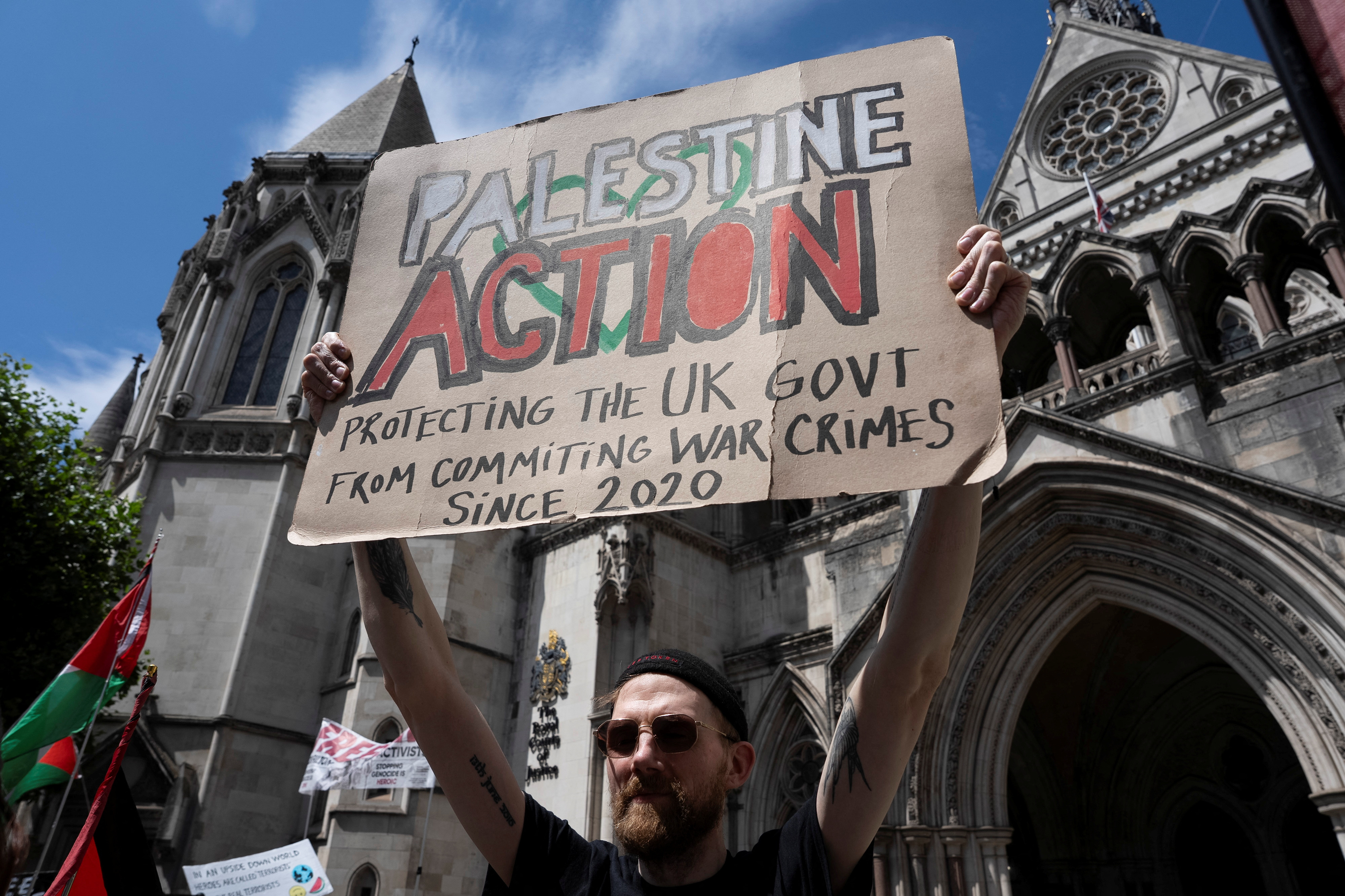 A supporter of pro-Palestinian campaign organization Palestine Action holds a banner outside London's High Court in London