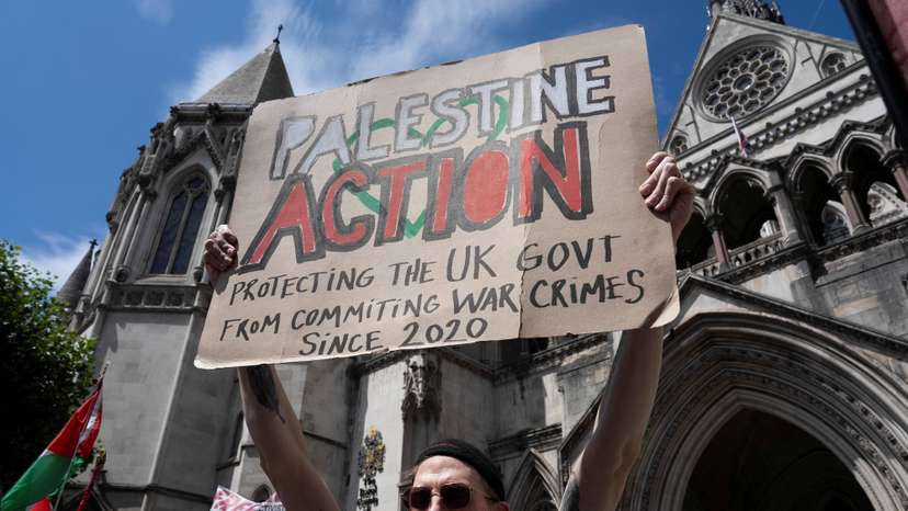 A supporter of pro-Palestinian campaign organization Palestine Action holds a banner outside London's High Court in London