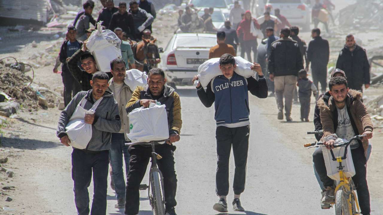 Palestinians carry aid unloaded from a truck, amid the ongoing conflict between Israel and Hamas, in Gaza City