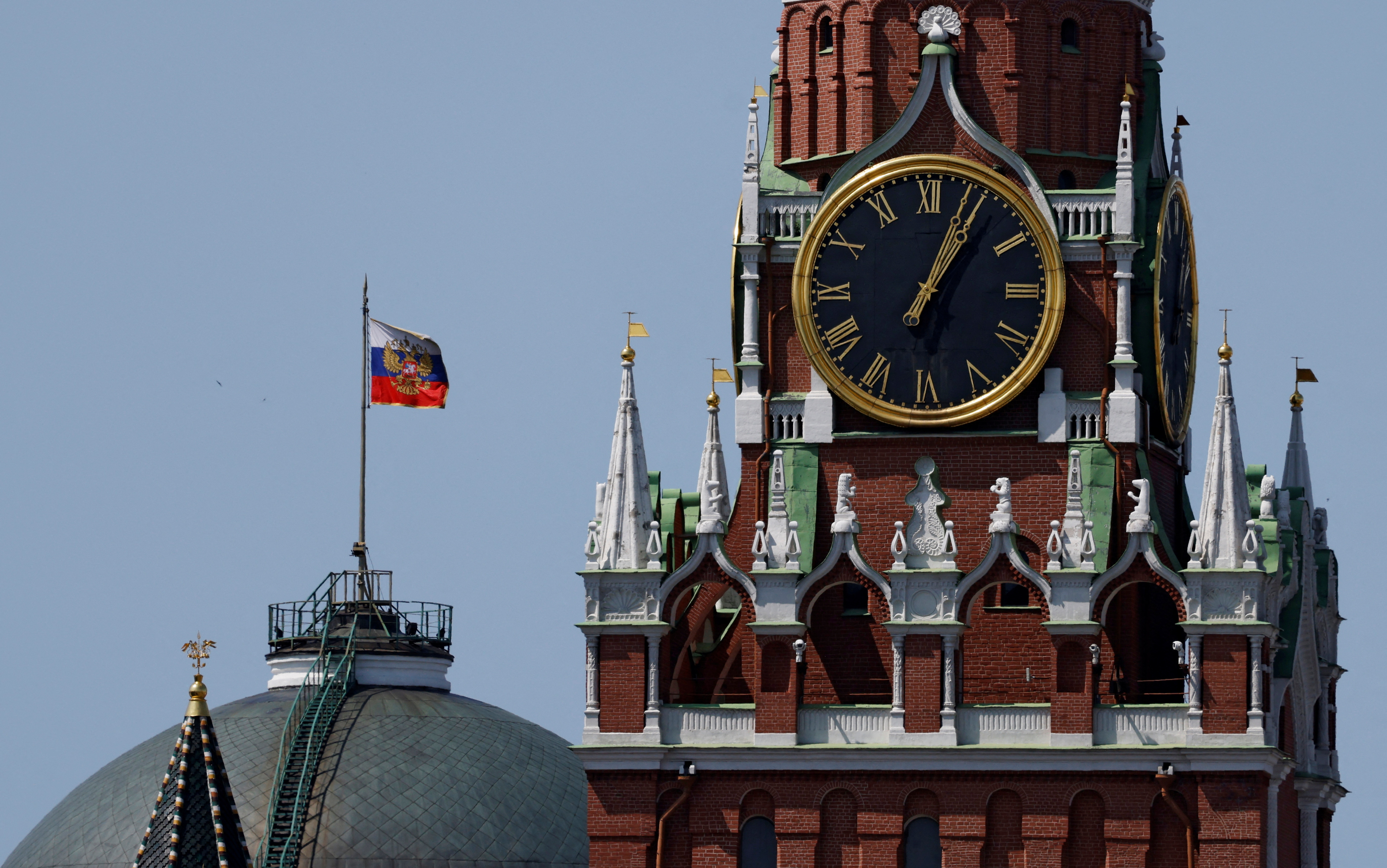 The Russian flag flies on the dome of the Kremlin Senate building behind Spasskaya Tower in Moscow