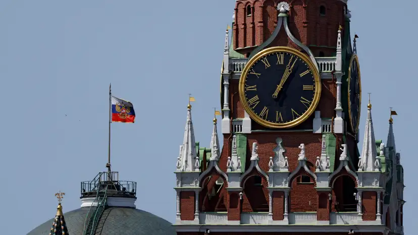 The Russian flag flies on the dome of the Kremlin Senate building behind Spasskaya Tower in Moscow