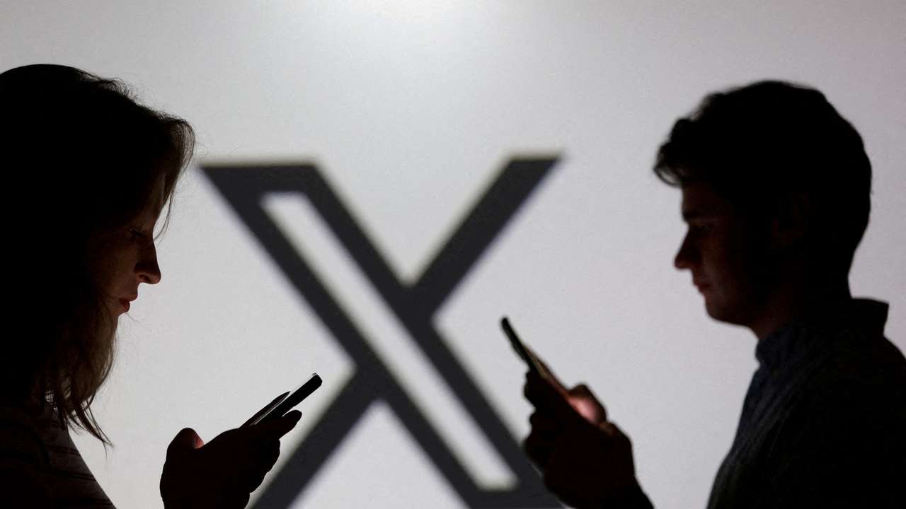 FILE PHOTO: Illustration shows teenagers pose for a photo while holding smartphones in front of a X logo