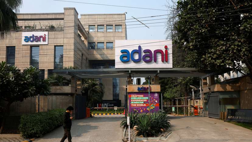 A man walks past a corporate office of Adani Group in Gurugram