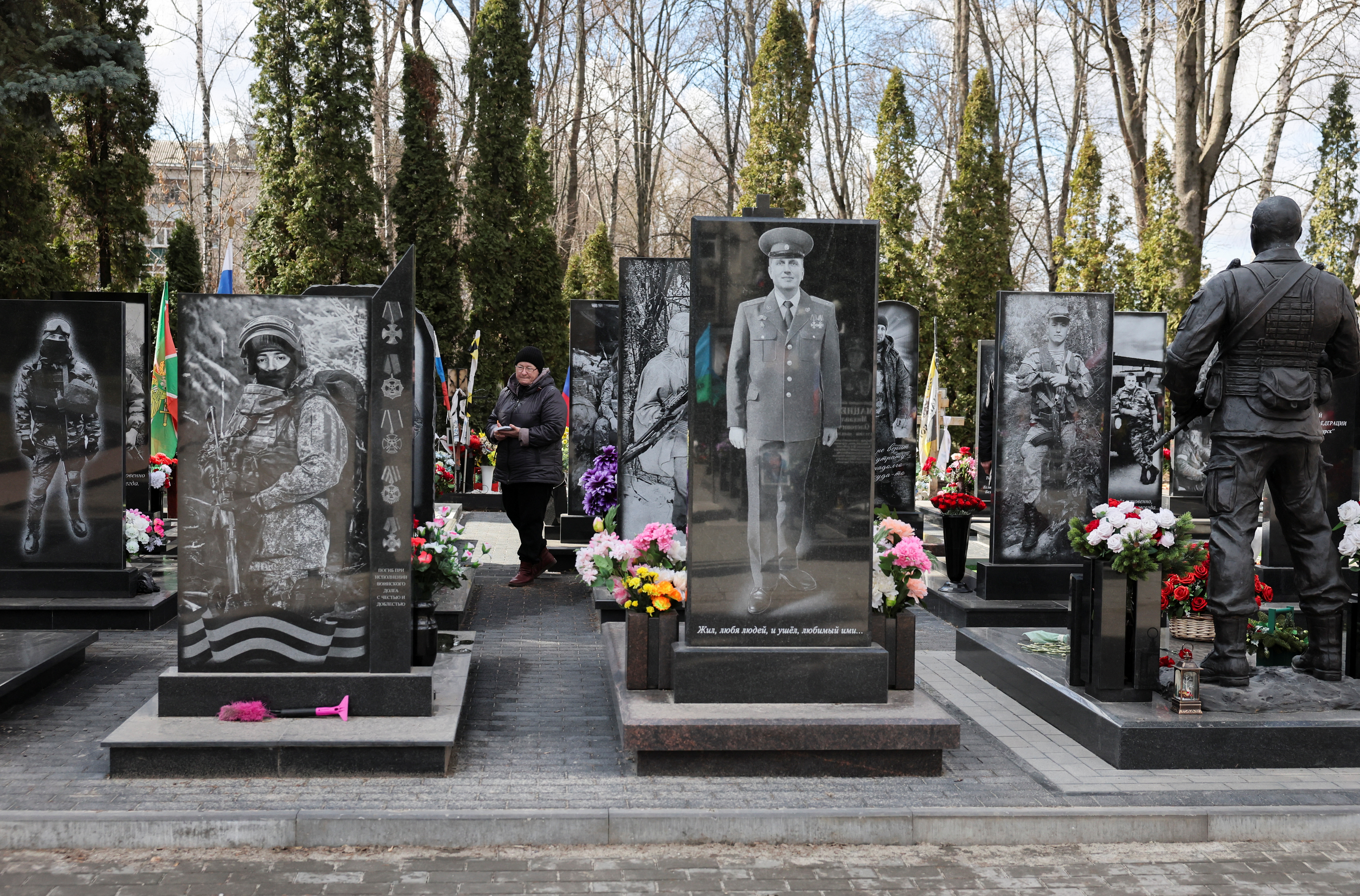A woman walks at a cemetery amid graves of Russian service members, who were killed in the course of Russia-Ukraine conflict, at a World War Two memorial in the city of Kursk