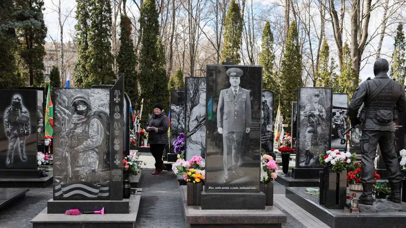 A woman walks at a cemetery amid graves of Russian service members, who were killed in the course of Russia-Ukraine conflict, at a World War Two memorial in the city of Kursk