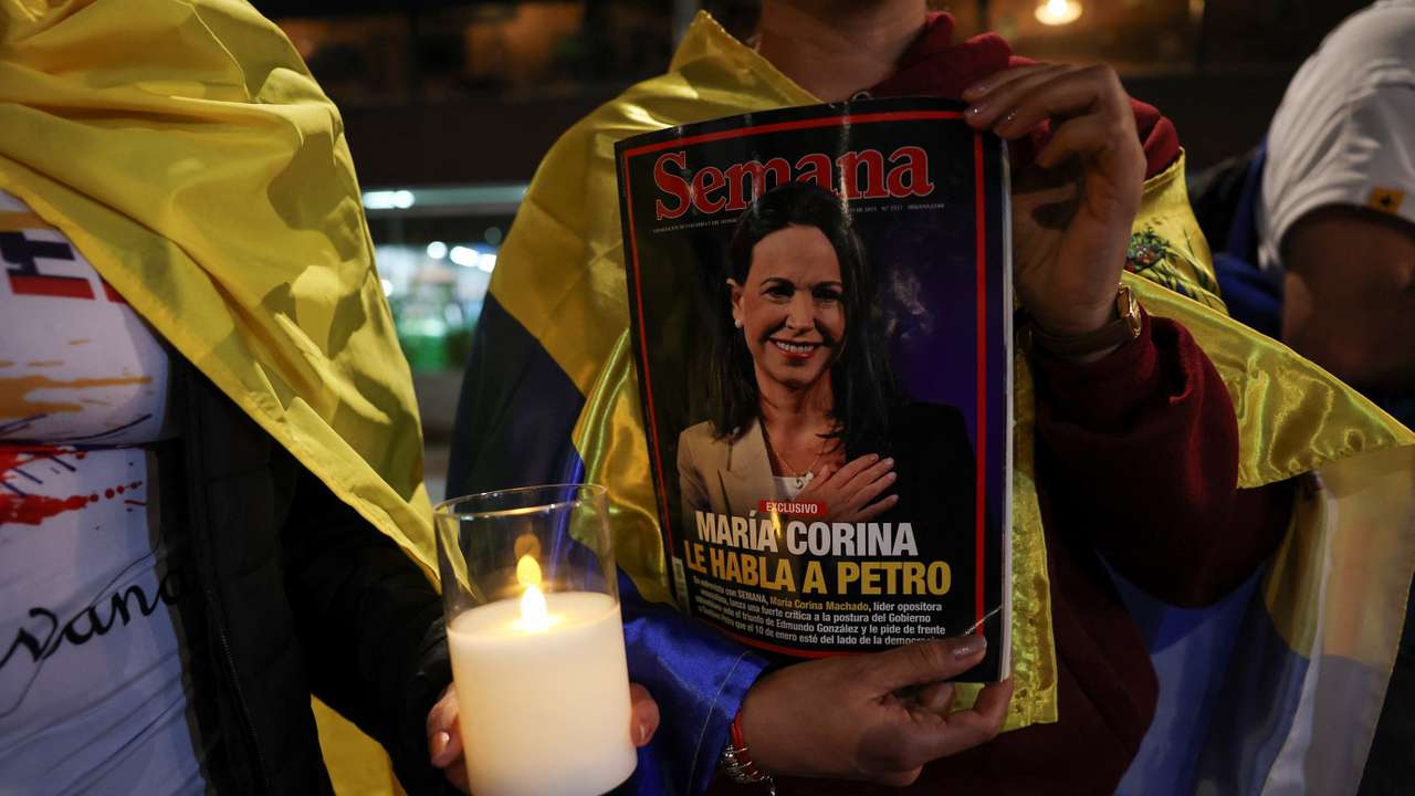 People hold a candle and a magazine with an image of Nobel Peace Prize winner Maria Corina Machado, as Venezuelans living in Colombia gather for a global march in support of Machado in Bogota, Colombia, December 6, 2025. REUTERS/Luisa Gonzalez