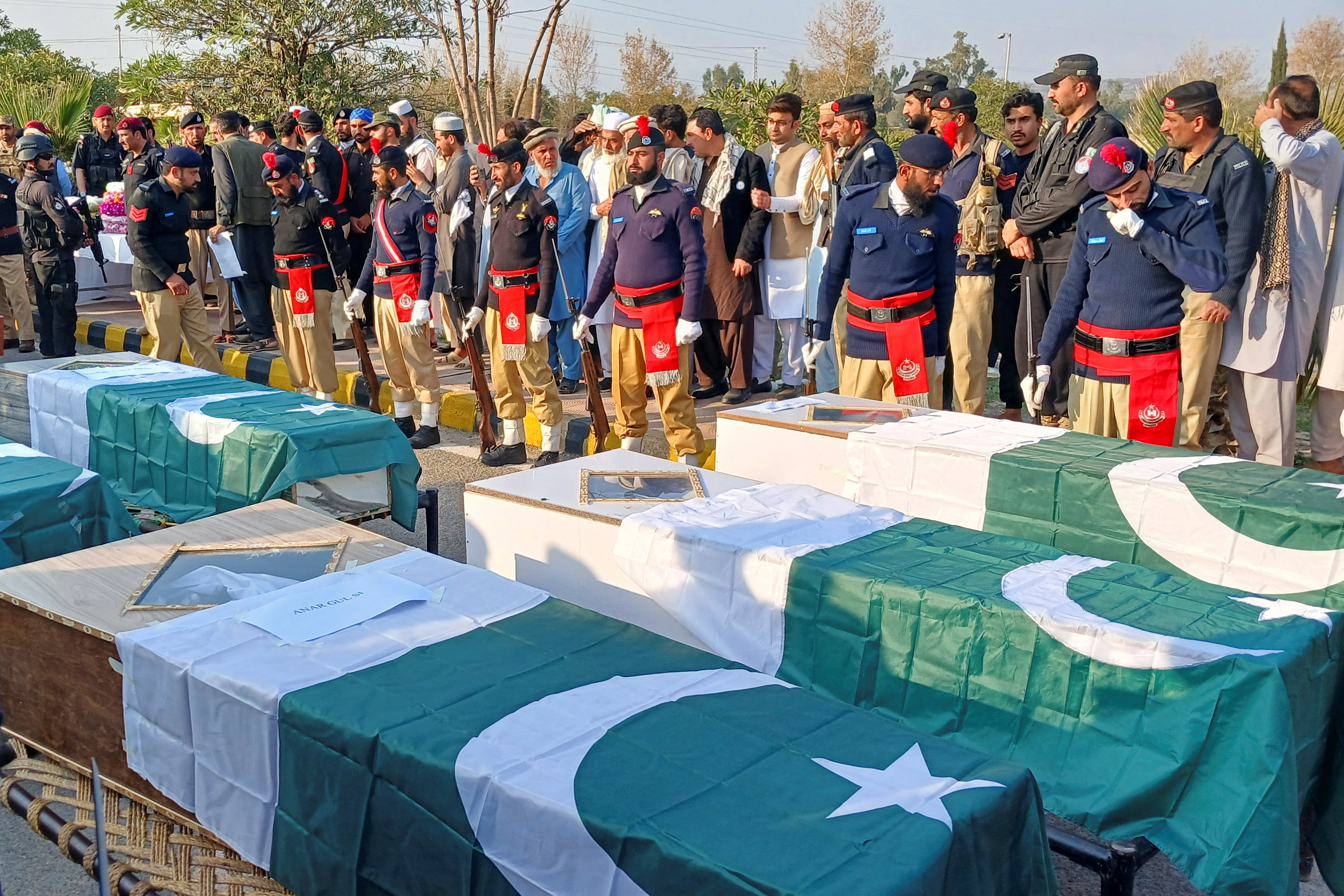 Police officers and residents gather beside Pakistani flag-draped coffins of police officers, who were killed following a terrorist attack on a police vehicle, during a funeral in Kohat