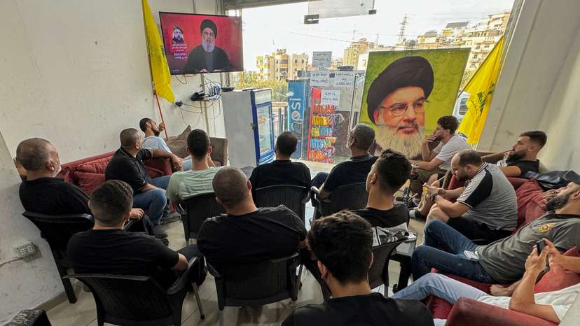 People watch Lebanon's Hezbollah leader Sayyed Hassan Nasrallah delivering a televised address, as they sit at a cafe in Sidon