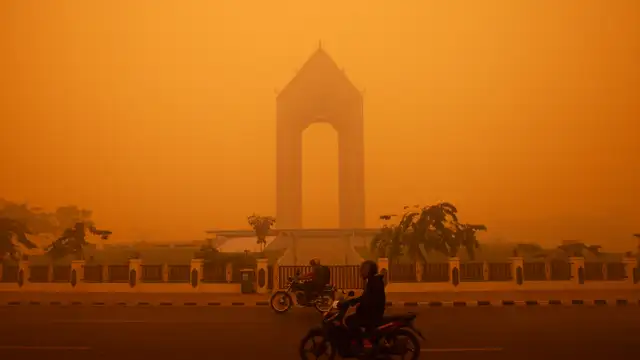 Motociclistas andam na manhã do dia 14 de outubro em Kalimantan, na região indonésia da ilha de Bornéu, em meio à fumaça vinda dos incêndios florestais.
