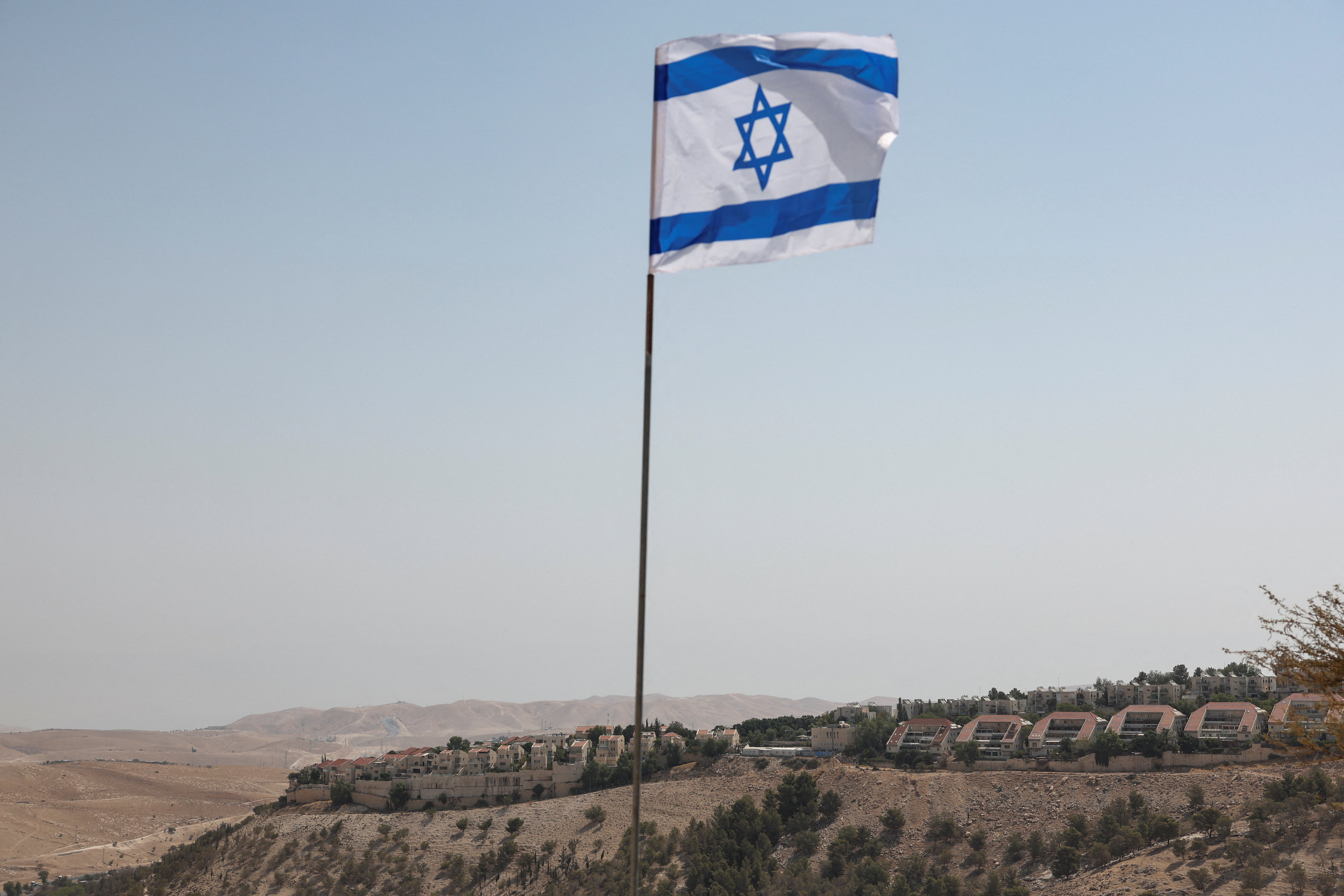 Israeli flag flutters, as part of the Israeli settlement of Maale Adumim is visible in the background, in the Israeli-occupied West Bank