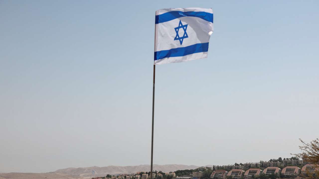 Israeli flag flutters, as part of the Israeli settlement of Maale Adumim is visible in the background, in the Israeli-occupied West Bank