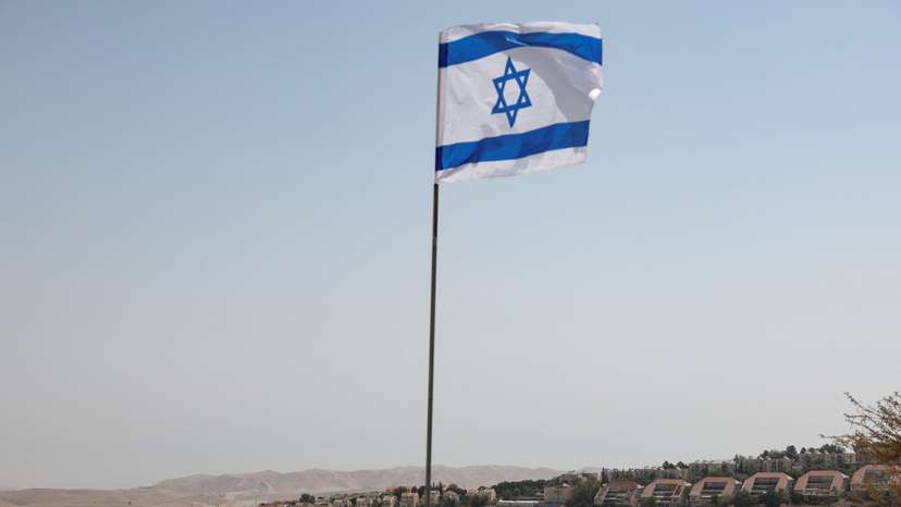 Israeli flag flutters, as part of the Israeli settlement of Maale Adumim is visible in the background, in the Israeli-occupied West Bank