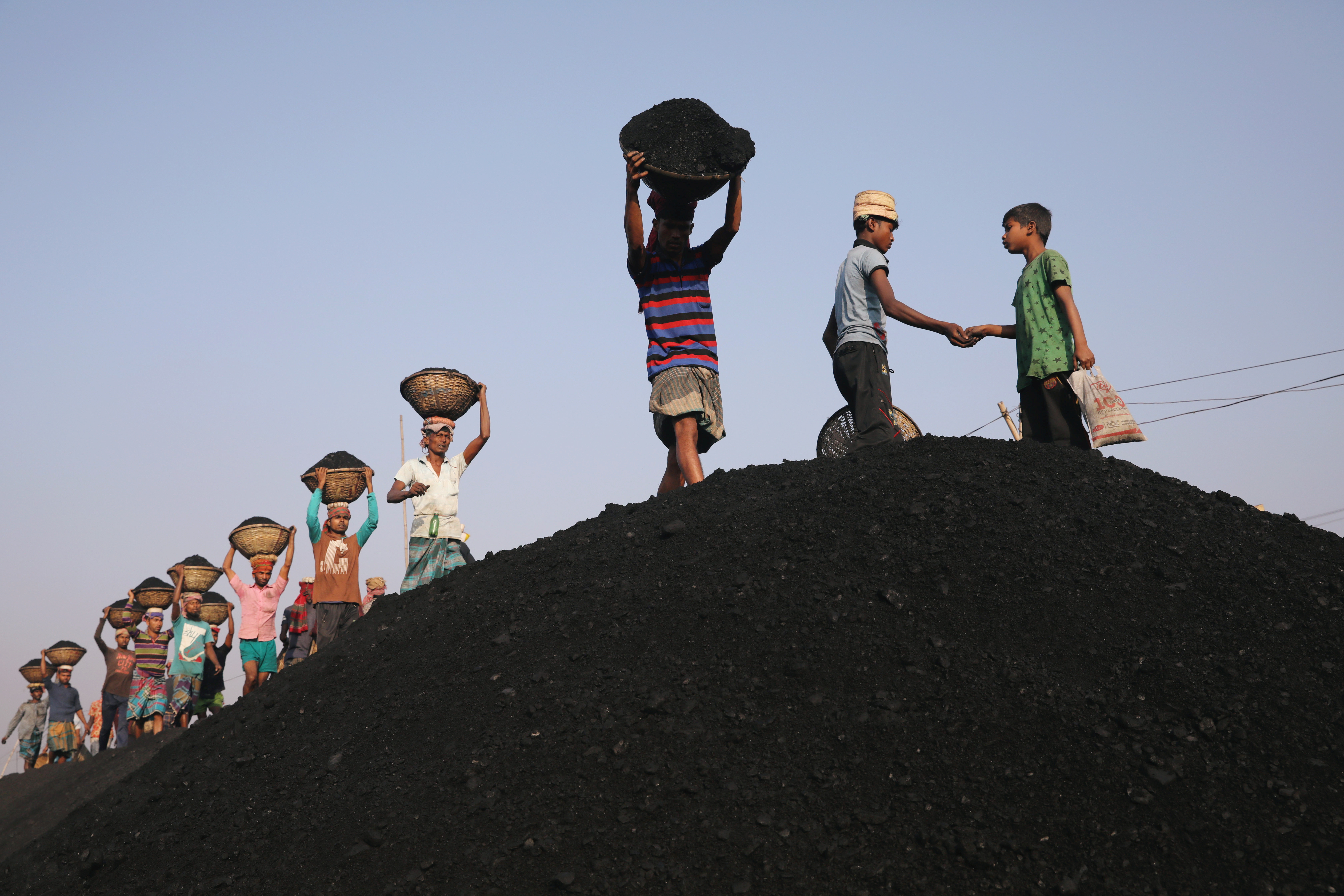 Coal workers are seen at a market as they unload a ferry in Dhaka