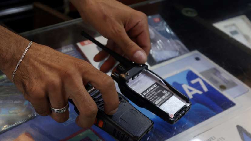 A vendor shows walkie-talkie devices without batteries at an electronic store in Sidon