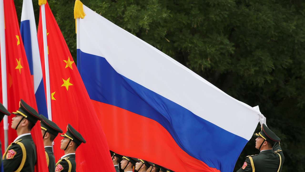 A military officer adjusts a Russian flag ahead of a welcome ceremony in Beijing
