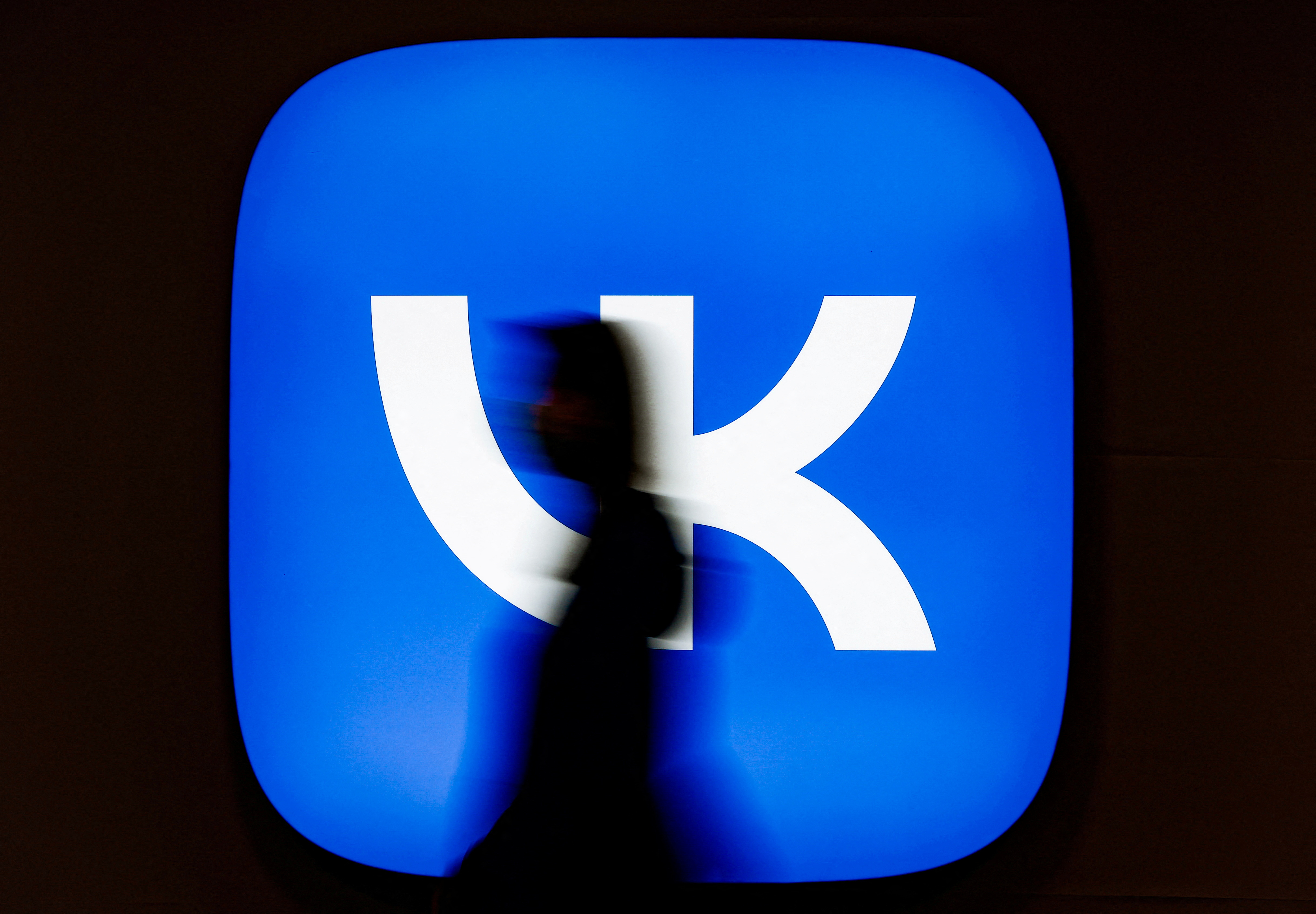 FILE PHOTO: An employee of Russian internet company VK walks past the company's logo at its headquarters in Moscow