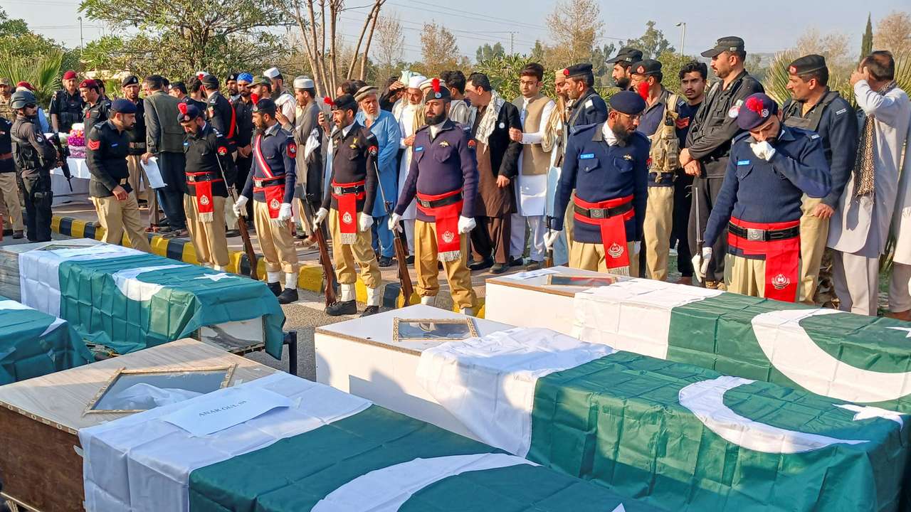 Police officers and residents gather beside Pakistani flag-draped coffins of police officers, who were killed following a terrorist attack on a police vehicle, during a funeral in Kohat