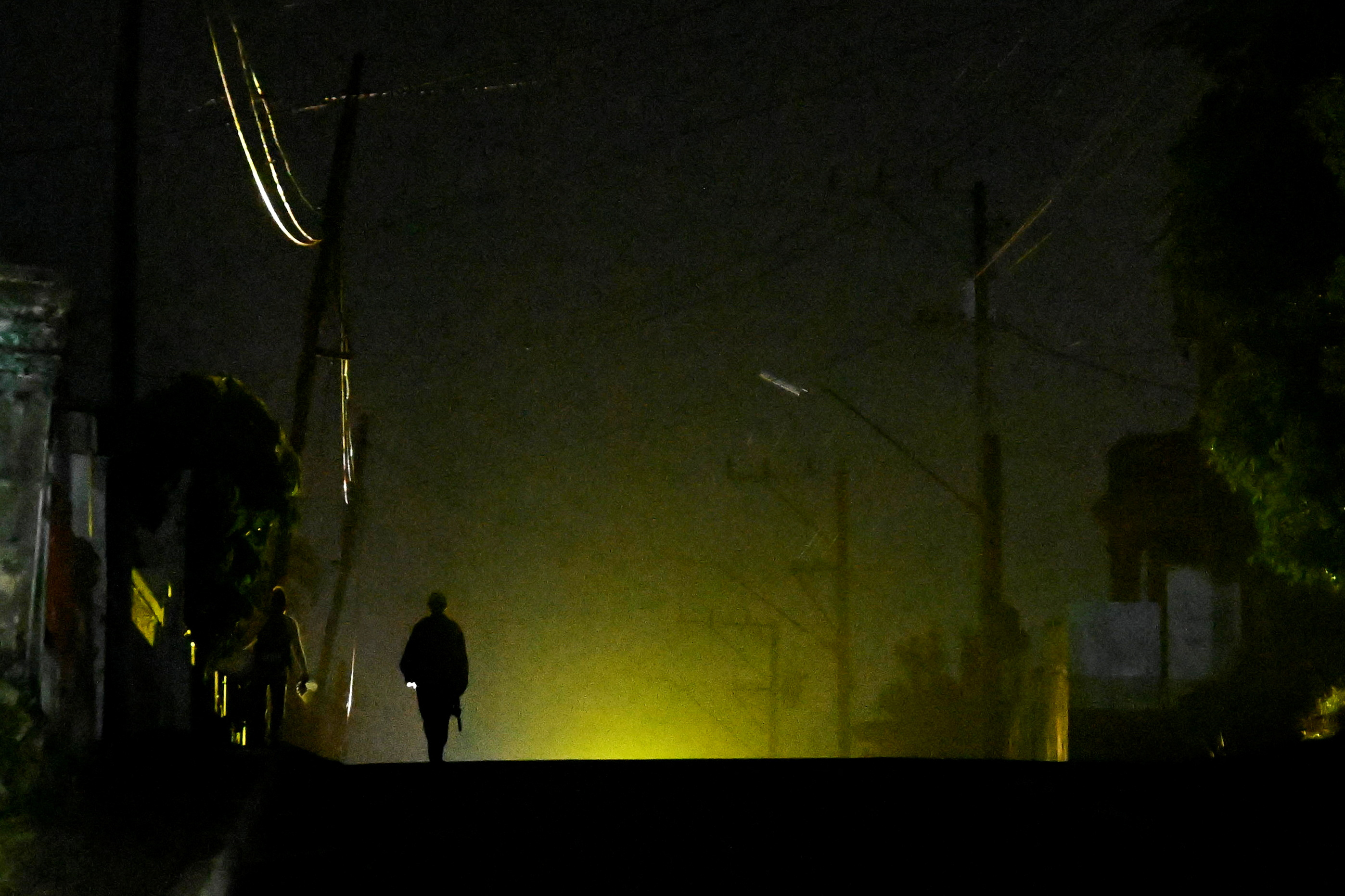A man walks on the street during a blackout as Cuba struggles to ease power cuts amid reduced fuel supplies from Venezuela, in Havana, Cuba November 18, 2025. REUTERS/Norlys Perez