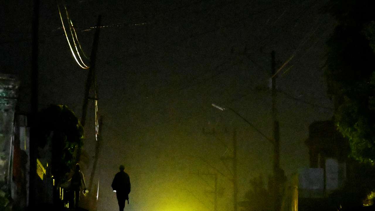 A man walks on the street during a blackout as Cuba struggles to ease power cuts amid reduced fuel supplies from Venezuela, in Havana, Cuba November 18, 2025. REUTERS/Norlys Perez