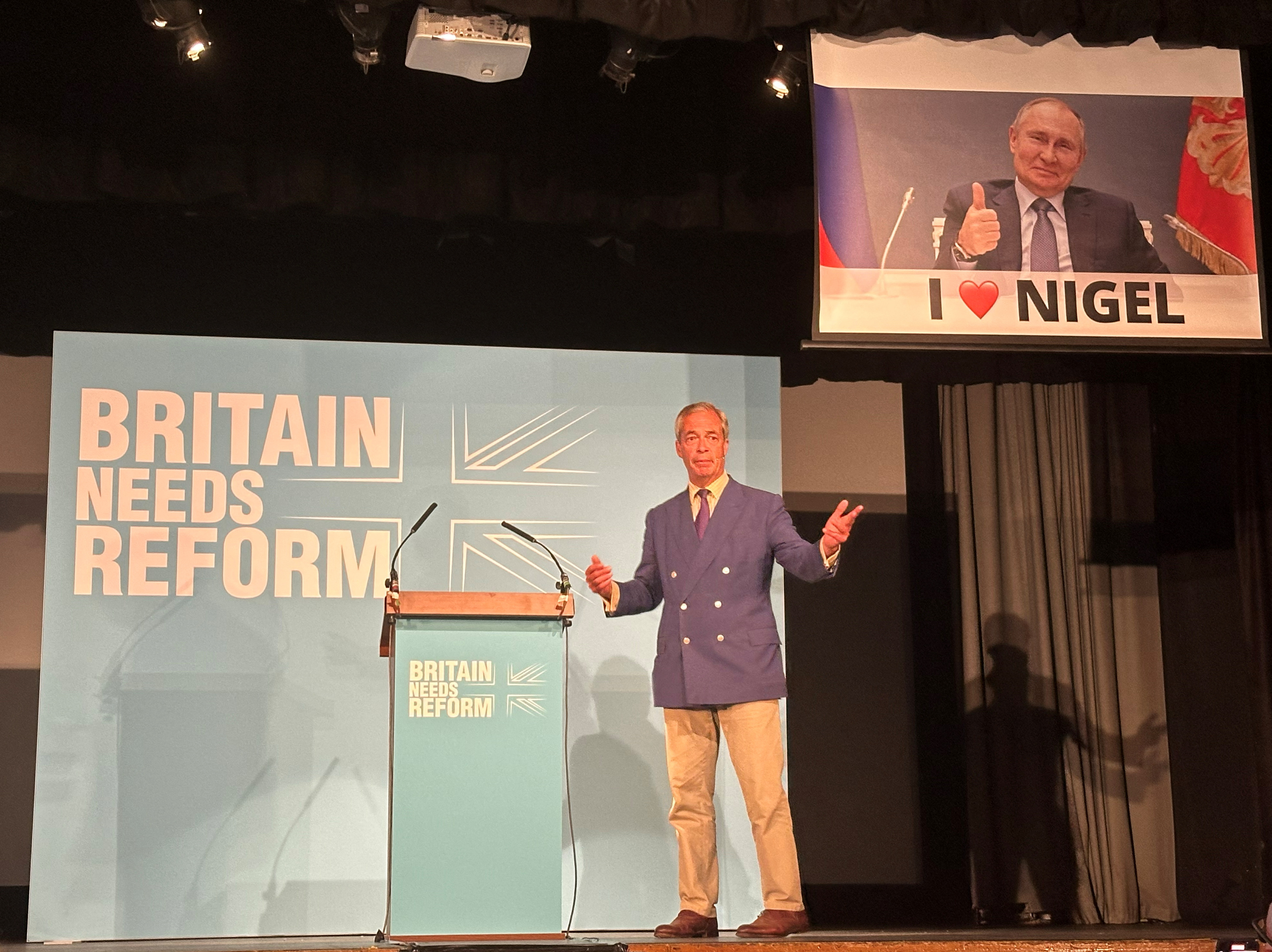 A remote-controlled screen operated by the political activist group, Led By Donkeys, lowers as Reform UK leader Nigel Farage speaks in Walton-on-the-Naze