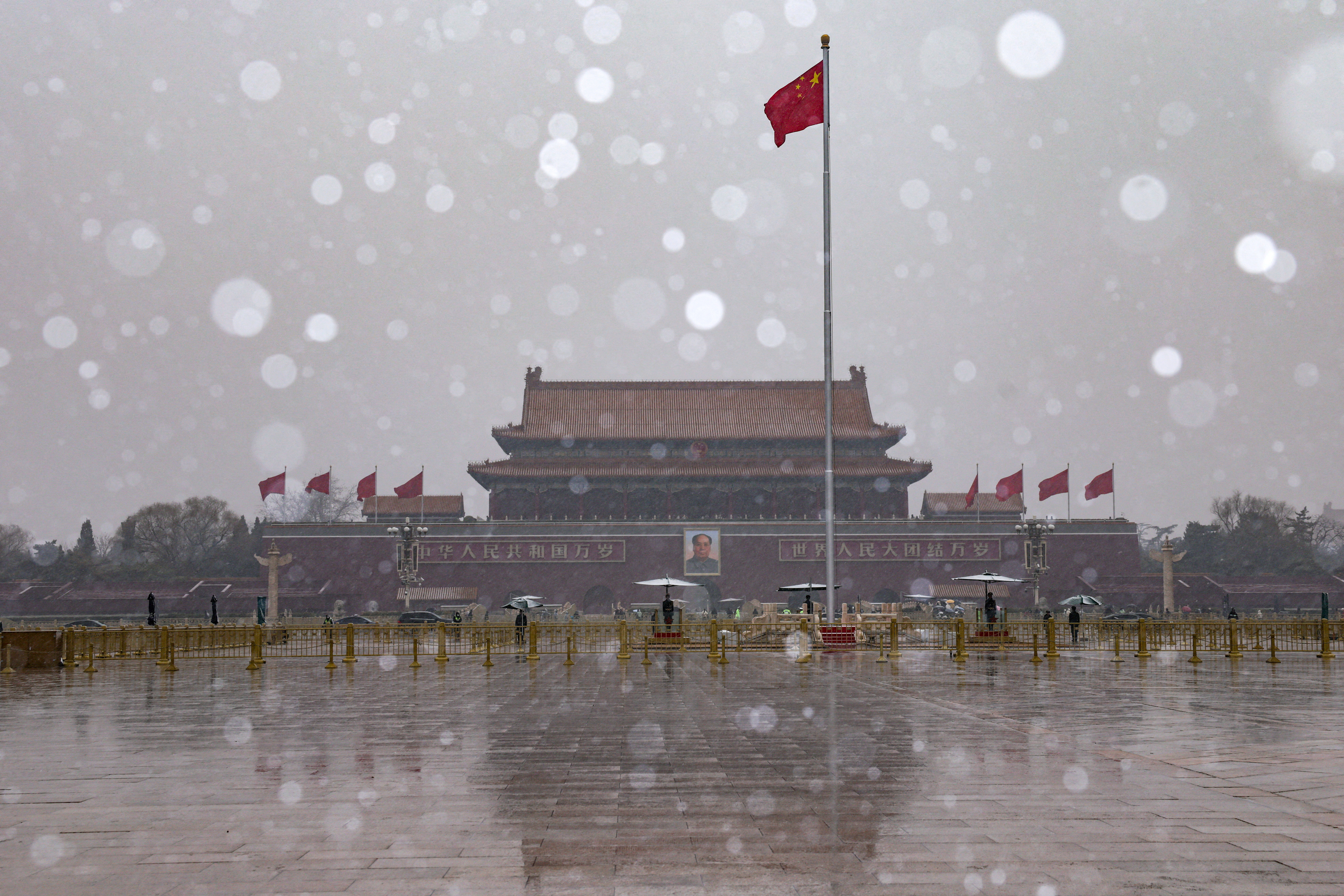 Chinese national flag flutters near Tiananmen Gate amid snowfall before the opening sessions of the annual CPPCC