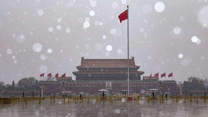 Chinese national flag flutters near Tiananmen Gate amid snowfall before the opening sessions of the annual CPPCC