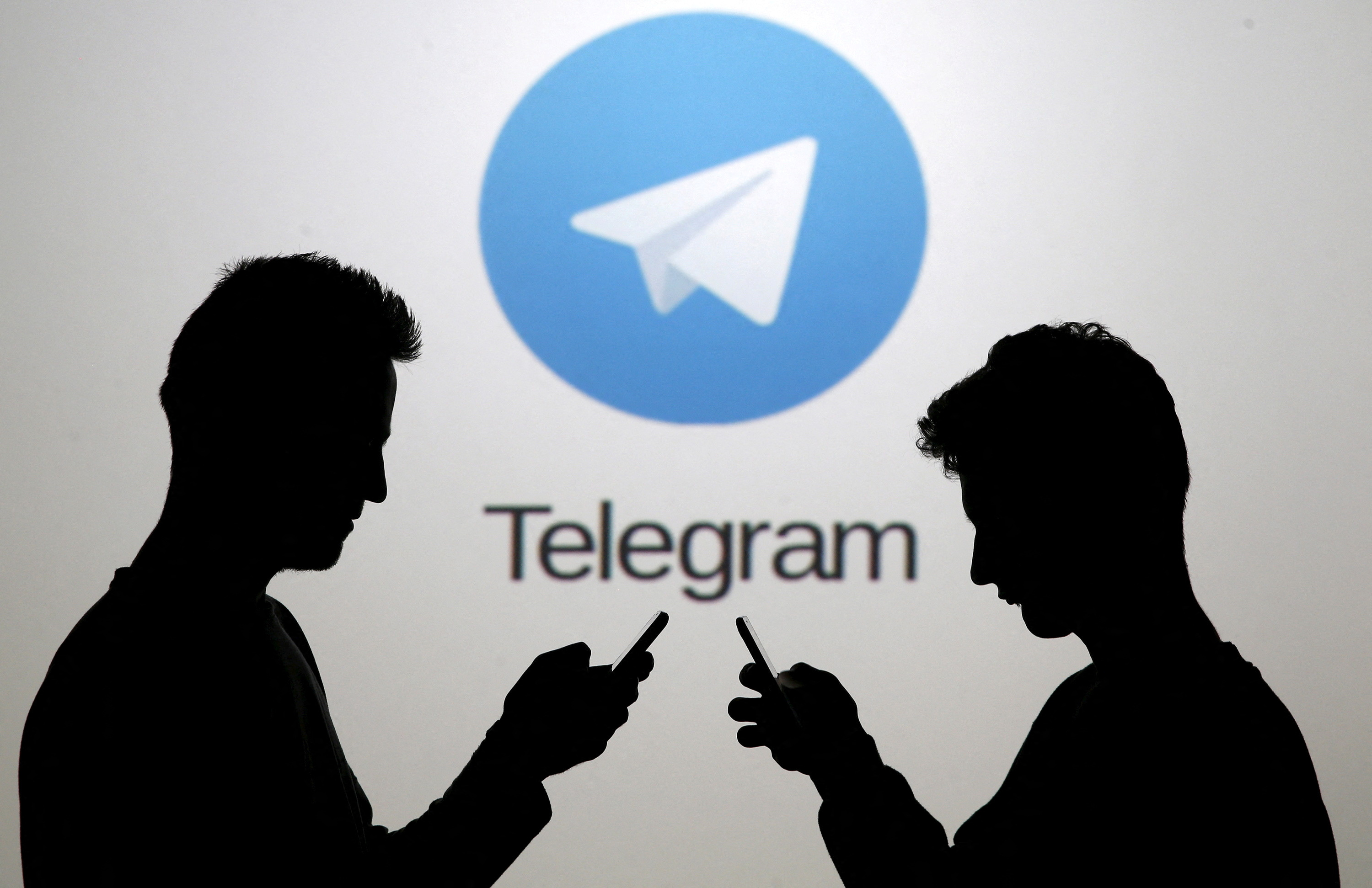 FILE PHOTO: Two men pose with smartphones in front of a screen showing the Telegram logo in this picture illustration taken in Zenica