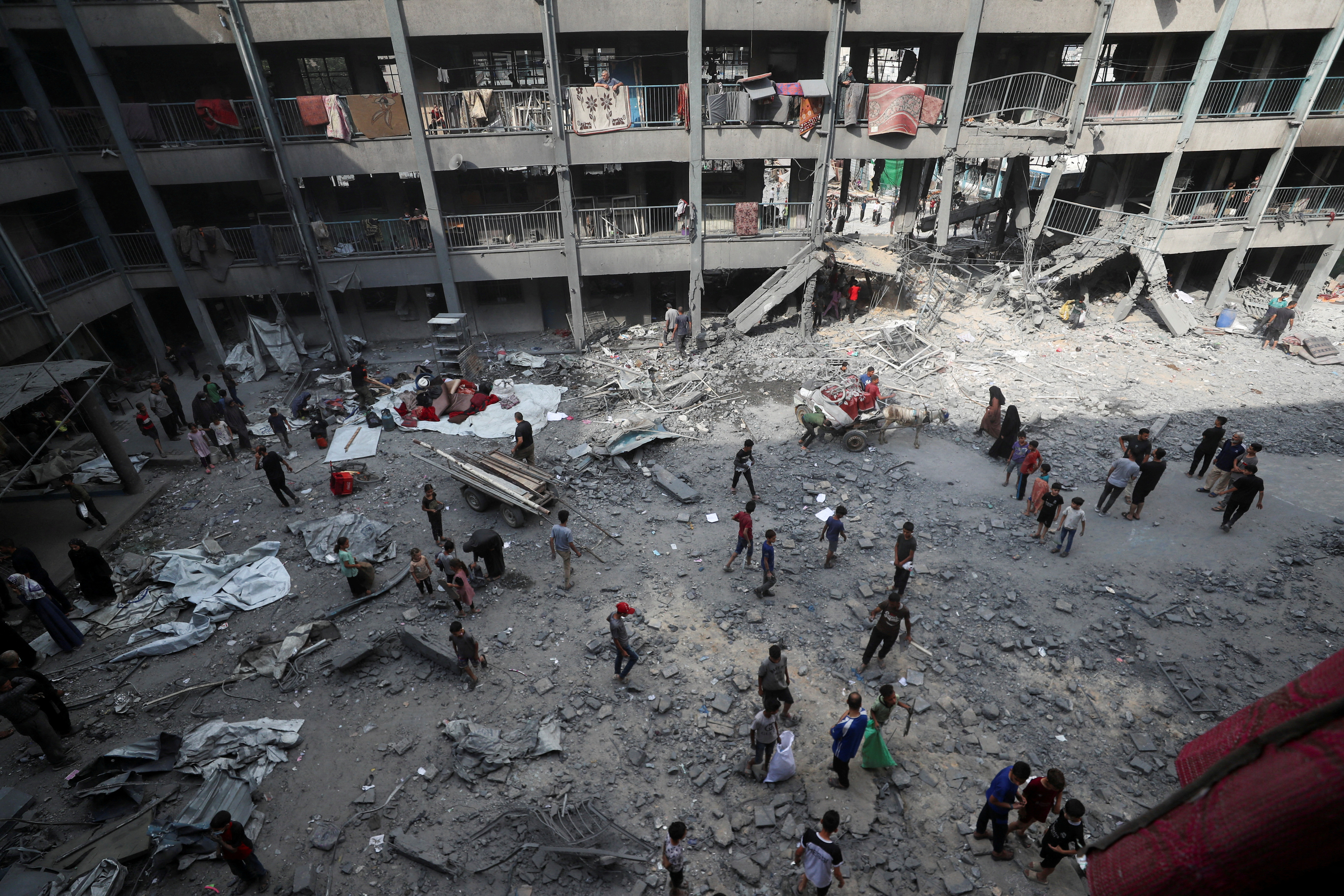 Palestinians inspect the damage at an UNRWA school sheltering displaced people that was hit in an Israeli air strike, in Gaza City