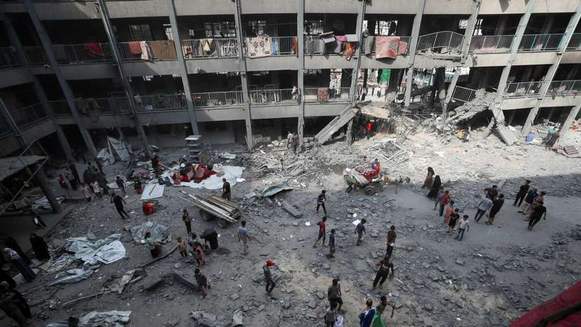 Palestinians inspect the damage at an UNRWA school sheltering displaced people that was hit in an Israeli air strike, in Gaza City