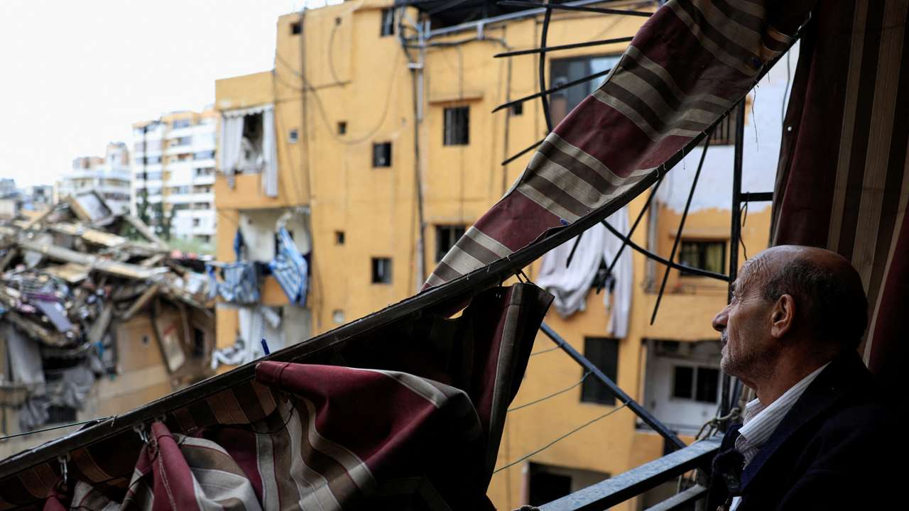 Displaced Lebanese man Zahi Hijazi stands on the balcony of his damaged apartment in Beirut's southern suburbs