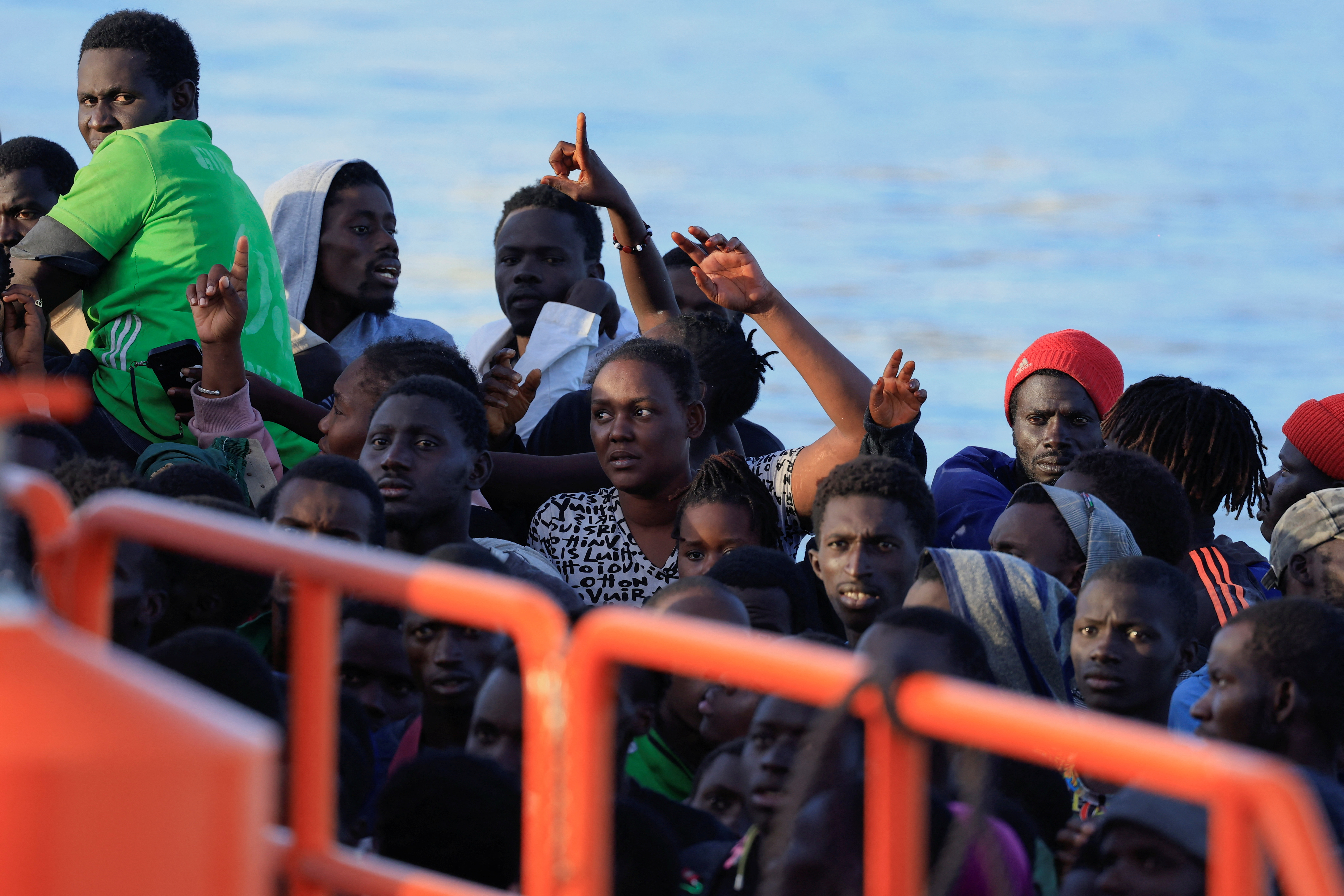 Several migrants wait to disembark from a wooden boat in the port of Arguineguin