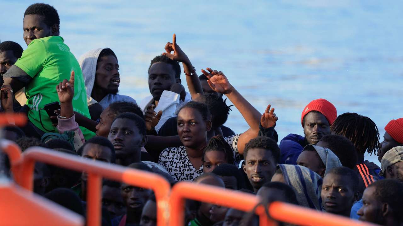 Several migrants wait to disembark from a wooden boat in the port of Arguineguin