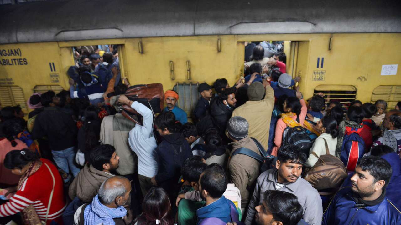 People, including Hindu pilgrims on their way to attend the "Maha Kumbh Mela", or the Great Pitcher Festival, jostle to board a train at the New Delhi Railway Station